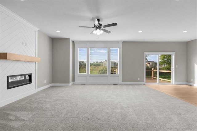 unfurnished living room featuring light carpet, plenty of natural light, and a large fireplace