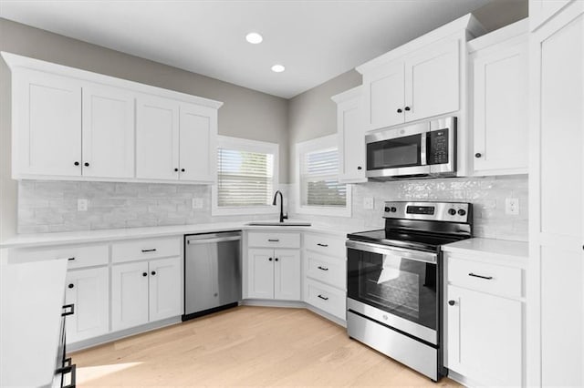 kitchen featuring light wood-style flooring, a sink, stainless steel appliances, light countertops, and white cabinets