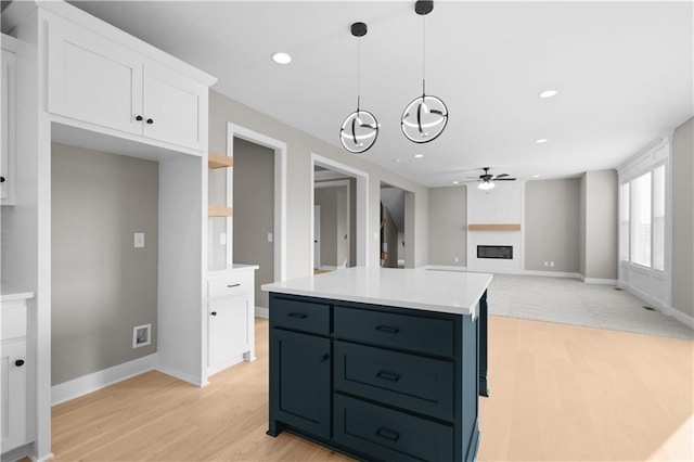 kitchen with a kitchen island, light hardwood / wood-style flooring, pendant lighting, white cabinetry, and ceiling fan