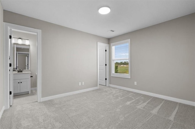 unfurnished bedroom featuring light carpet and ensuite bathroom