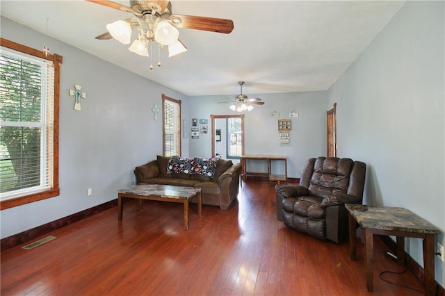 living area with a healthy amount of sunlight, baseboards, visible vents, and dark wood-style flooring