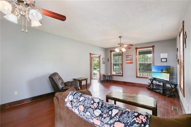 living room featuring a ceiling fan, baseboards, visible vents, and dark wood-style flooring