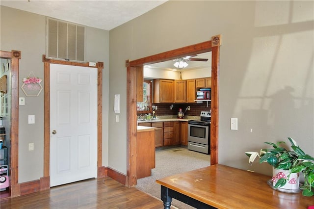 kitchen with visible vents, decorative backsplash, electric stove, brown cabinets, and light countertops