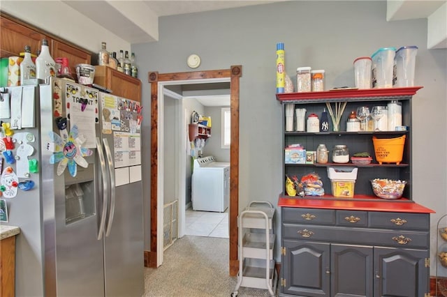 kitchen featuring light carpet, open shelves, stainless steel refrigerator with ice dispenser, and washer and dryer