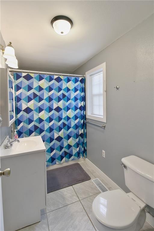 bathroom featuring toilet, vanity, visible vents, a shower with curtain, and tile patterned floors