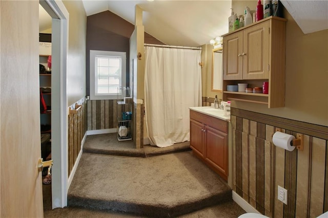 full bath featuring curtained shower, a wainscoted wall, vaulted ceiling, and vanity