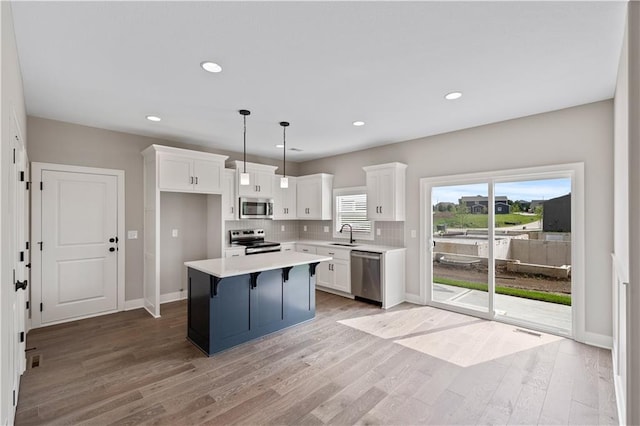 kitchen featuring backsplash, stainless steel appliances, light hardwood / wood-style flooring, a center island, and hanging light fixtures