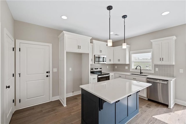 kitchen with hardwood / wood-style floors, sink, appliances with stainless steel finishes, tasteful backsplash, and hanging light fixtures