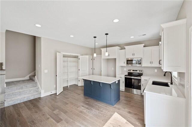 kitchen with appliances with stainless steel finishes, light hardwood / wood-style flooring, tasteful backsplash, sink, and a center island