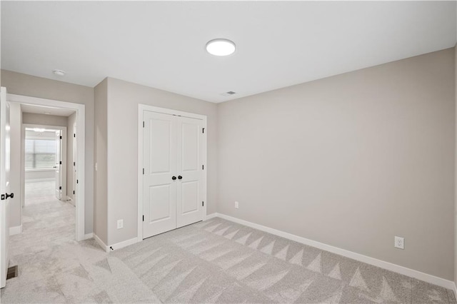 unfurnished bedroom with a closet and light carpet