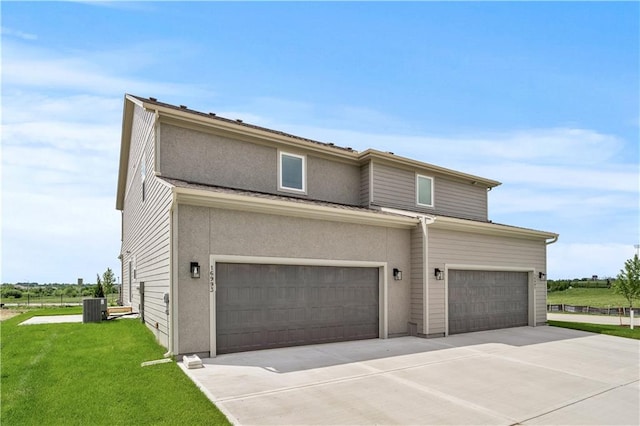 view of front of property with central AC unit, a front yard, and a garage