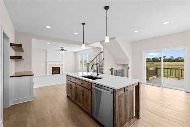 kitchen featuring a glass covered fireplace, open floor plan, a sink, wood finished floors, and dishwasher