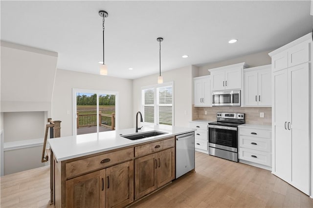 kitchen featuring sink, appliances with stainless steel finishes, a kitchen island with sink, tasteful backsplash, and white cabinets