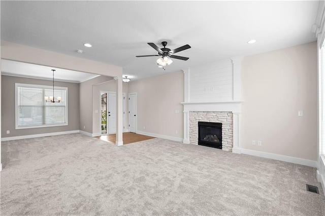 unfurnished living room featuring ceiling fan with notable chandelier, carpet, and a healthy amount of sunlight