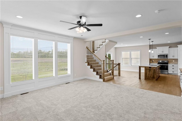 carpeted living room featuring sink and ceiling fan