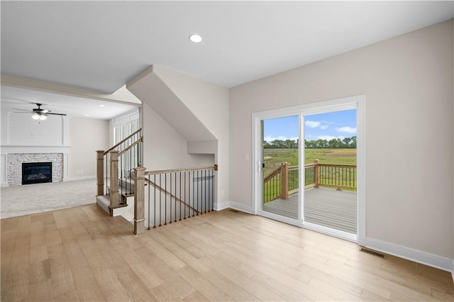 interior space featuring baseboards, visible vents, wood finished floors, and a glass covered fireplace