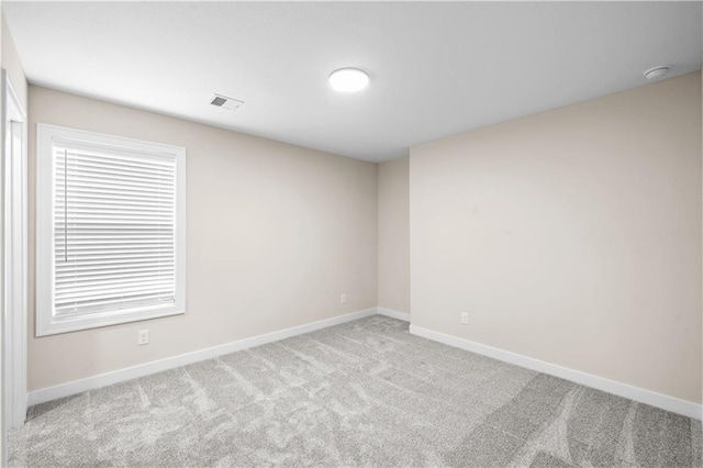 spare room featuring carpet flooring, visible vents, and baseboards