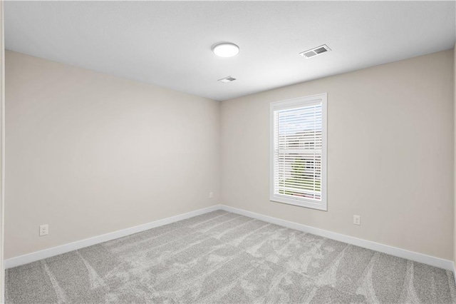 empty room featuring carpet flooring, visible vents, and baseboards