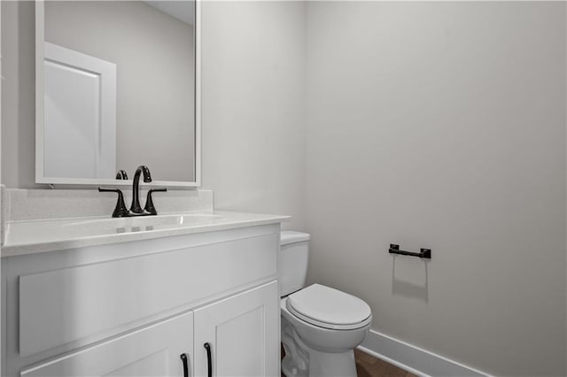 bathroom with baseboards, vanity, and toilet