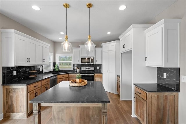 kitchen featuring a kitchen island, hardwood / wood-style floors, stainless steel appliances, white cabinets, and hanging light fixtures