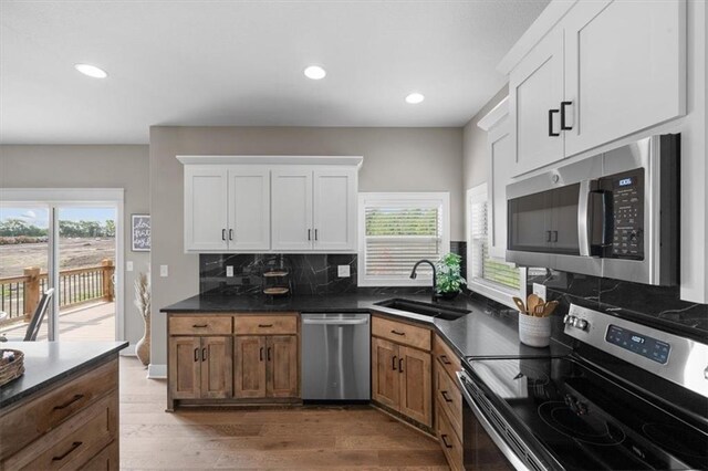 19019 W 169th Pl, Olathe, KS 66062 - kitchen featuring a sink, dark countertops, appliances with stainless steel finishes, wood finished floors, and decorative backsplash