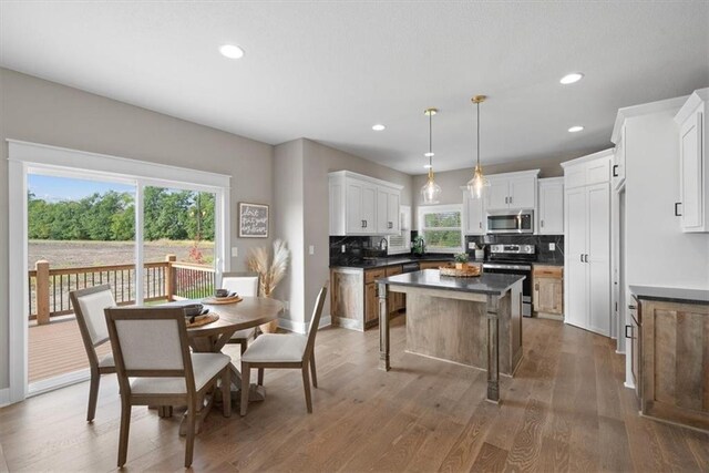19019 W 169th Pl, Olathe, KS 66062 - kitchen featuring tasteful backsplash, a kitchen island, wood finished floors, dark countertops, and stainless steel appliances