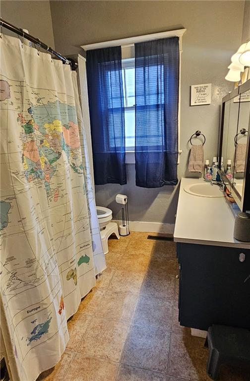 bathroom featuring walk in shower, vanity, and toilet