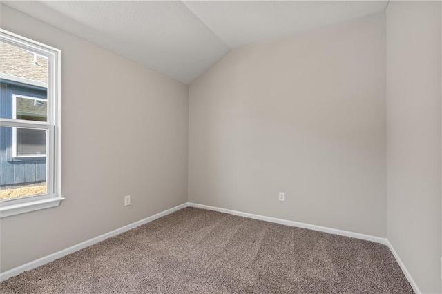 empty room with carpet, baseboards, and vaulted ceiling