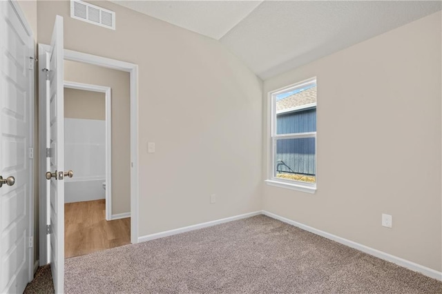 unfurnished bedroom featuring lofted ceiling, carpet, visible vents, and baseboards