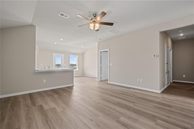 unfurnished living room with visible vents, vaulted ceiling, and wood finished floors