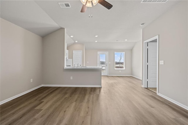 unfurnished living room with vaulted ceiling, light wood-type flooring, and visible vents