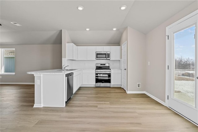 kitchen with white cabinets, light wood-style flooring, stainless steel appliances, a sink, and recessed lighting