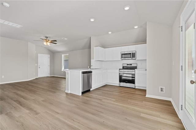 kitchen featuring a peninsula, white cabinetry, open floor plan, vaulted ceiling, and appliances with stainless steel finishes