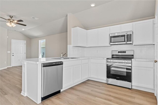 kitchen featuring light countertops, visible vents, appliances with stainless steel finishes, vaulted ceiling, and a sink