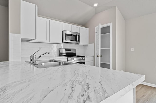 kitchen featuring a sink, light stone countertops, appliances with stainless steel finishes, and backsplash