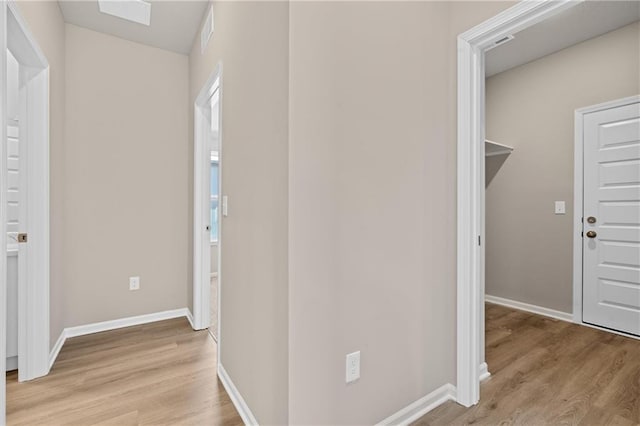 hallway with baseboards, visible vents, and light wood-style floors