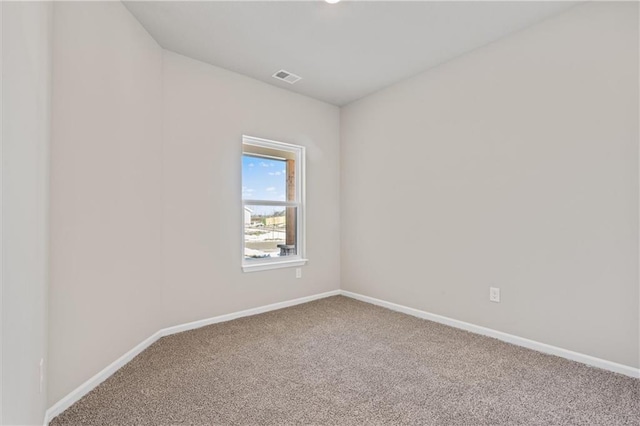 spare room featuring carpet, visible vents, and baseboards