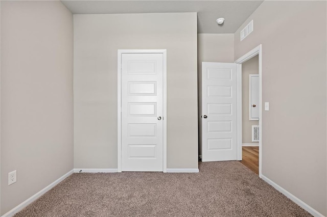 unfurnished bedroom with carpet, visible vents, and baseboards