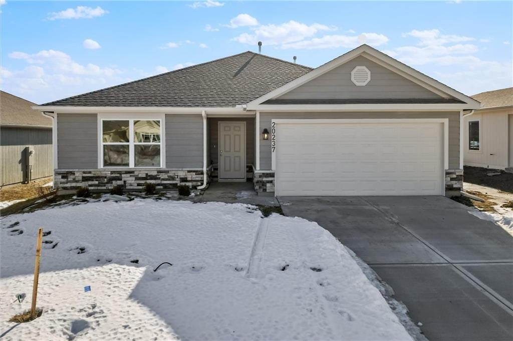 single story home featuring driveway, stone siding, roof with shingles, and an attached garage