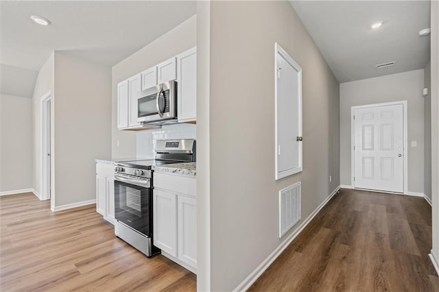 kitchen featuring stainless steel appliances, light wood-type flooring, and white cabinets