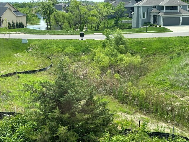 view of yard featuring a water view, driveway, and a garage