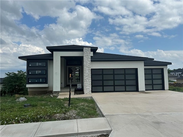 view of front facade featuring a garage, concrete driveway, stone siding, and stucco siding