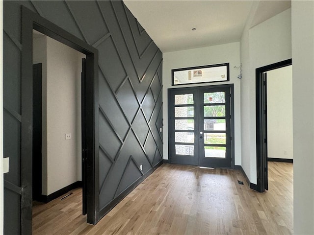 entryway featuring light wood-style floors, french doors, and baseboards