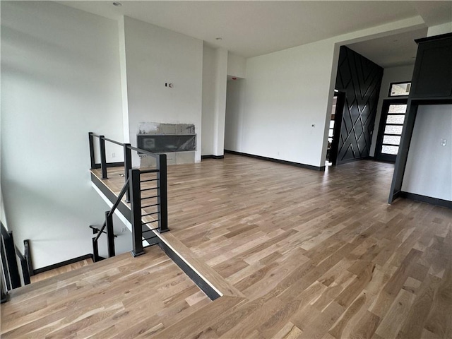 unfurnished living room with baseboards, light wood finished floors, and a barn door