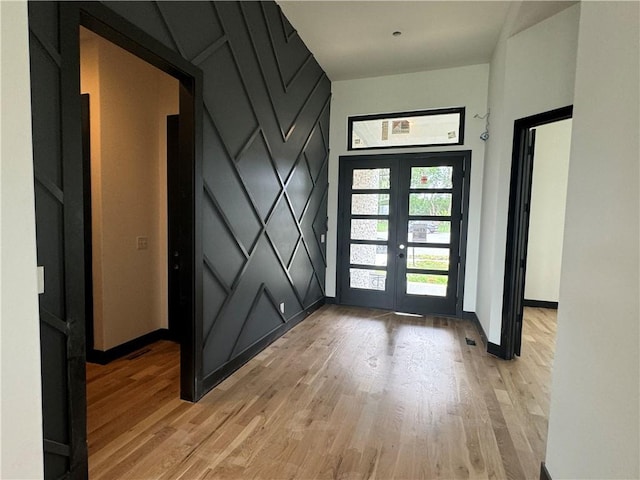 foyer entrance with light wood-type flooring, french doors, and baseboards