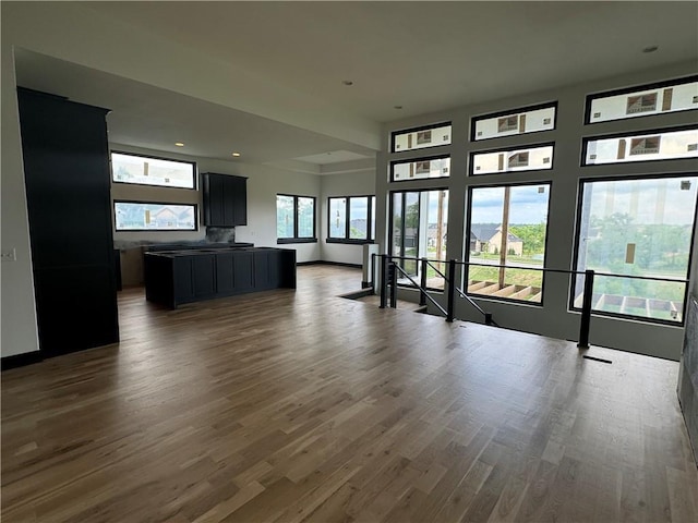 unfurnished living room featuring baseboards and dark wood-style flooring