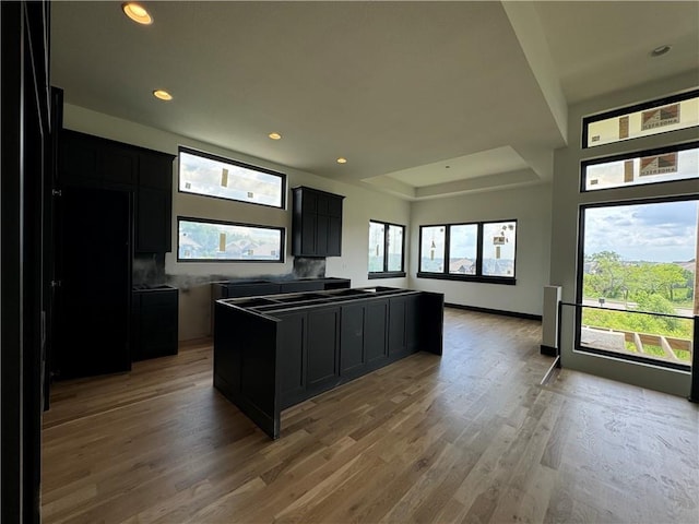 kitchen featuring a healthy amount of sunlight, recessed lighting, light wood-style flooring, and dark cabinets