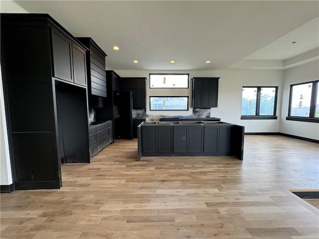 kitchen featuring freestanding refrigerator, baseboards, dark cabinetry, and light wood finished floors