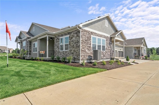 view of front of home with covered porch, stone siding, a yard, and stucco siding