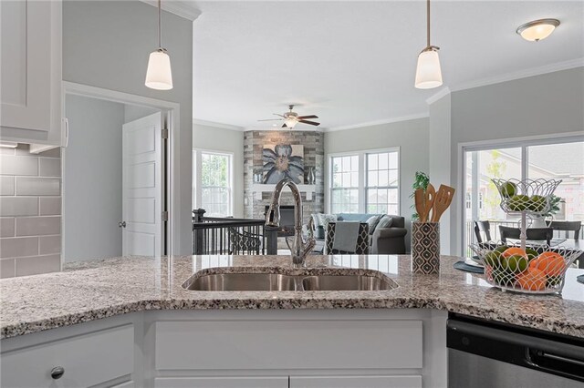 kitchen featuring stainless steel dishwasher, white cabinetry, light stone countertops, sink, and decorative light fixtures